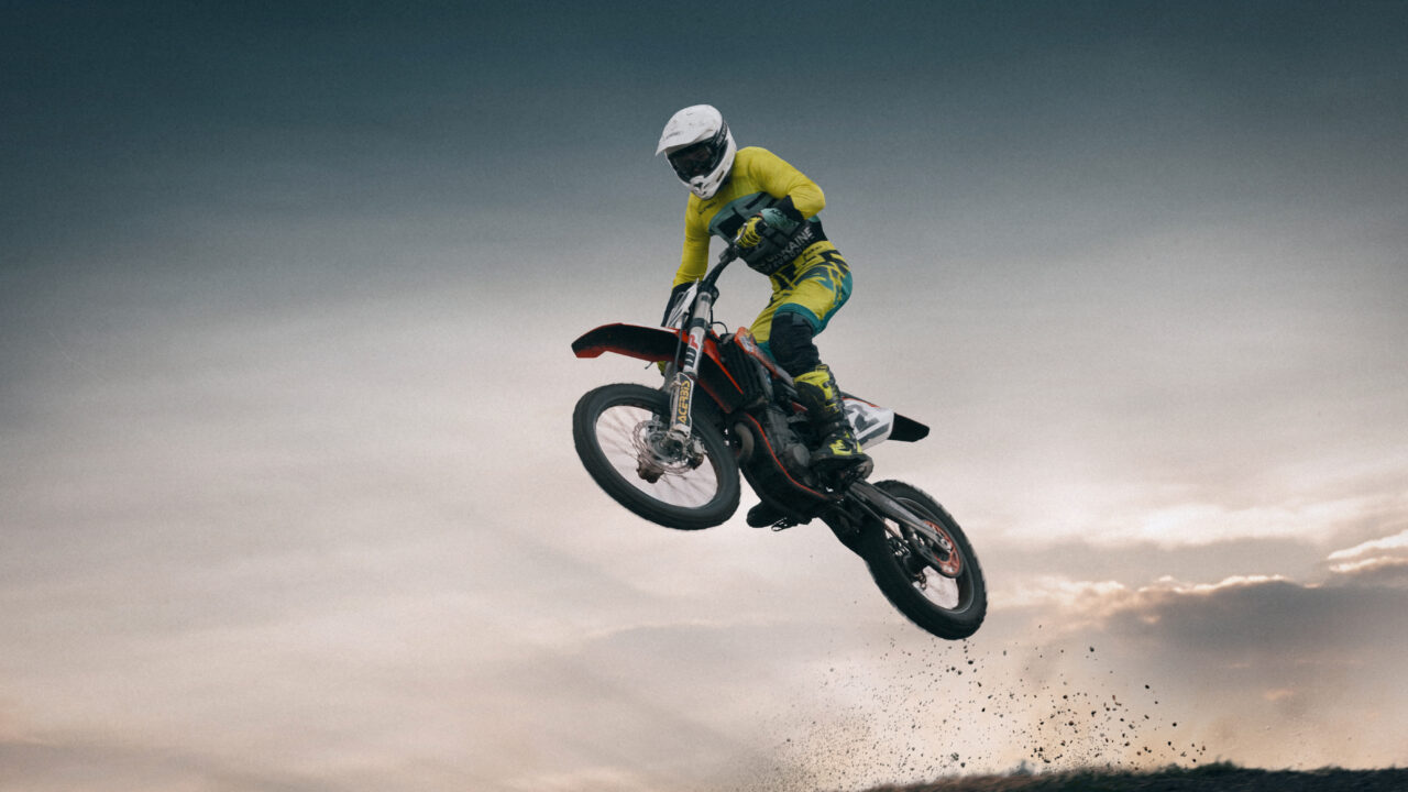 Pilote de motocross en position de base, debout sur les repose-pieds, buste avancé, coudes hauts