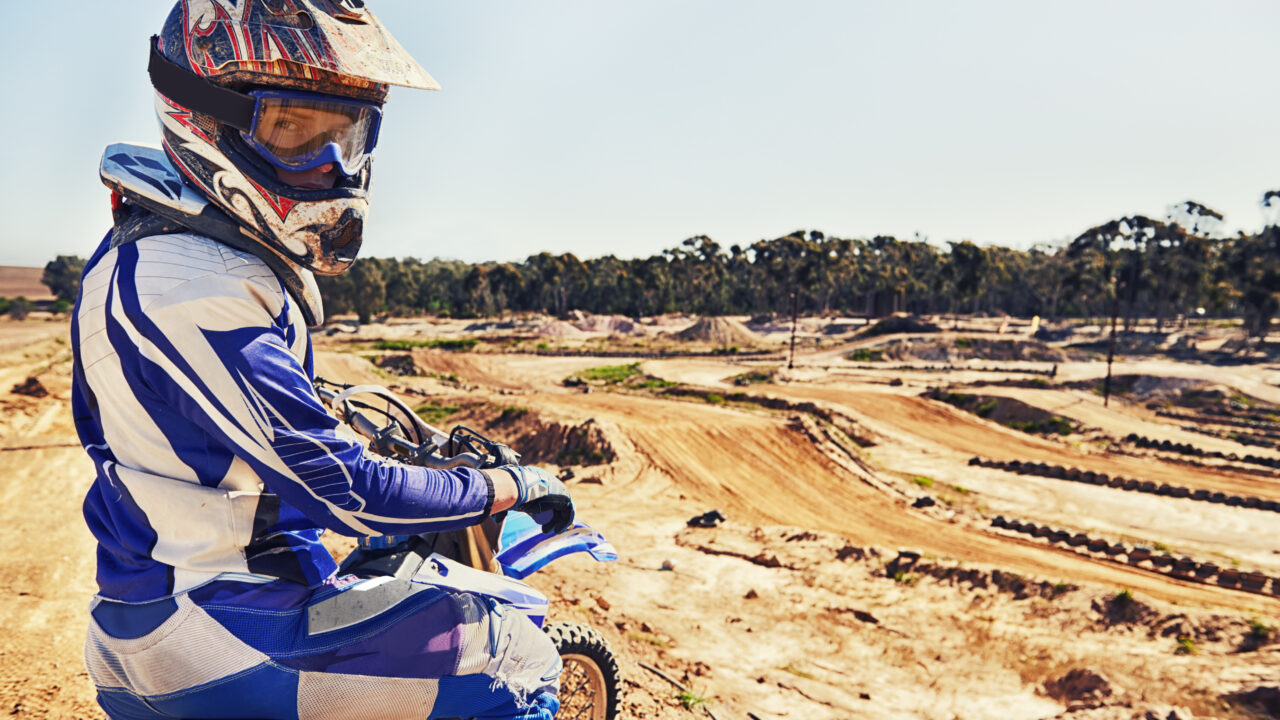 Pilote de motocross assis sur sa moto sur un terrain d'entraînement, séance de pratique