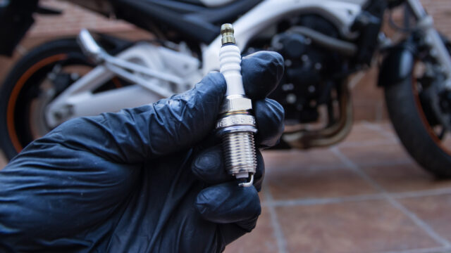 Main tenant une bougie d'allumage retirée d'une moto de motocross
