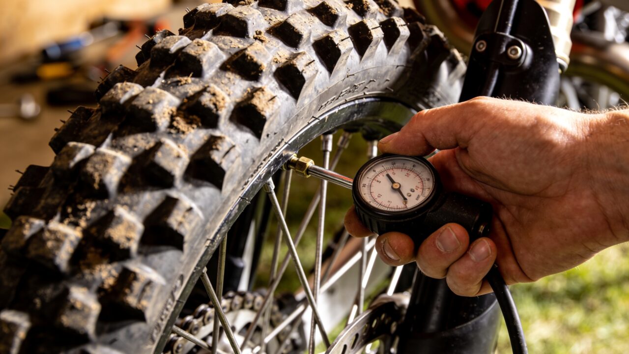 Contrôle de la pression d'un pneu à crampons de moto de motocross avec un manomètre