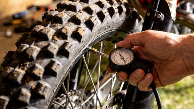 Contrôle de la pression d'un pneu à crampons de moto de motocross avec un manomètre
