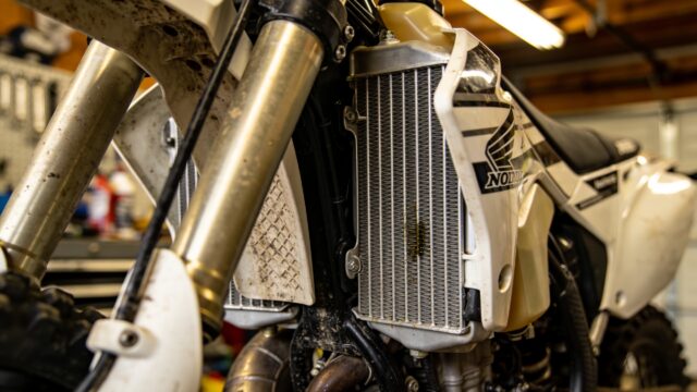 Radiateur avec ailettes visible sur une moto de motocross près du réservoir