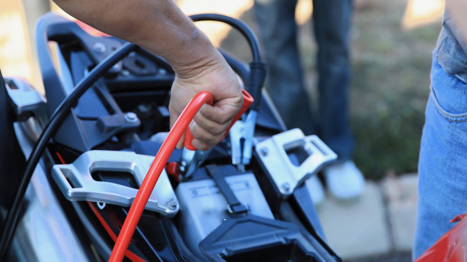Batterie de moto branchée sur un chargeur, câbles rouge et noir posés sur les cosses
