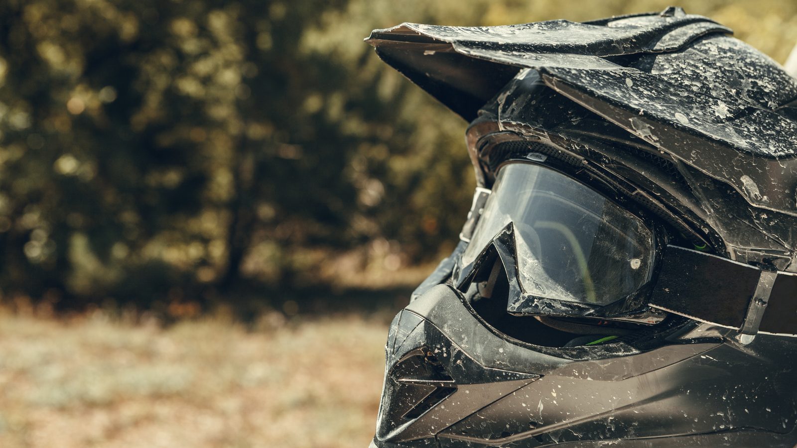 Casque de motocross couvert de poussière avec son masque posé sur l'écran