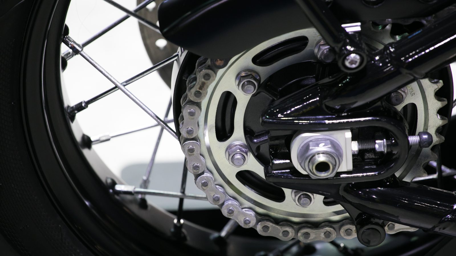 Chaîne et couronne arrière d'une moto vues de près, brin inférieur apparent
