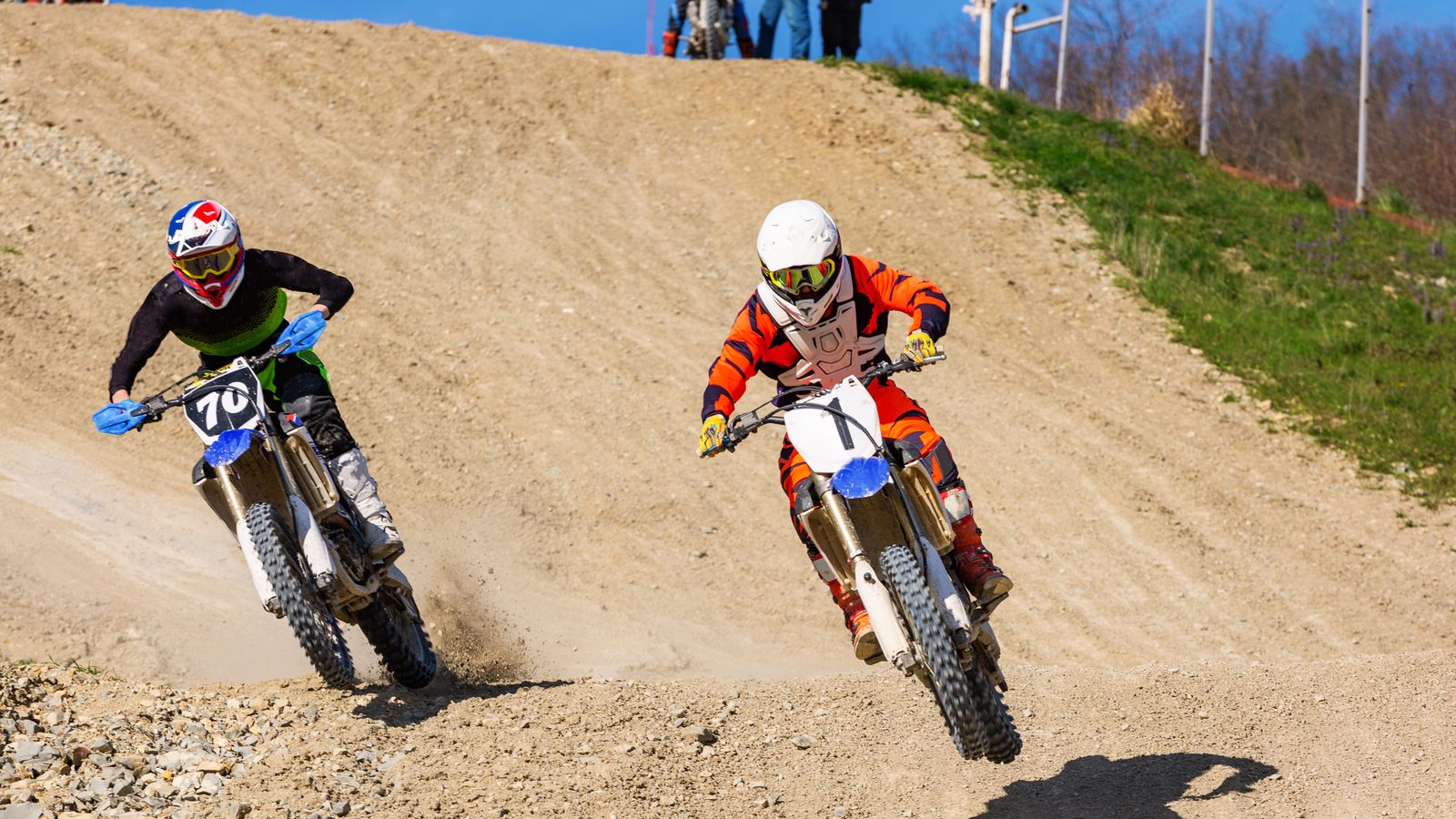 Deux pilotes de motocross roulant côte à côte dans la poussière sur un tracé de terre