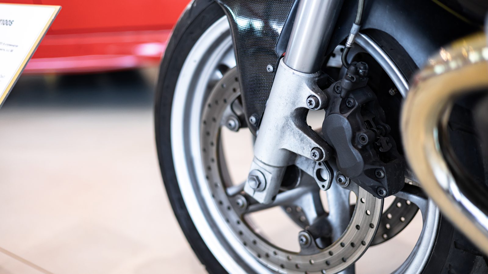 Gros plan sur la fourche avant d'une moto, tubes, roue et étrier visibles