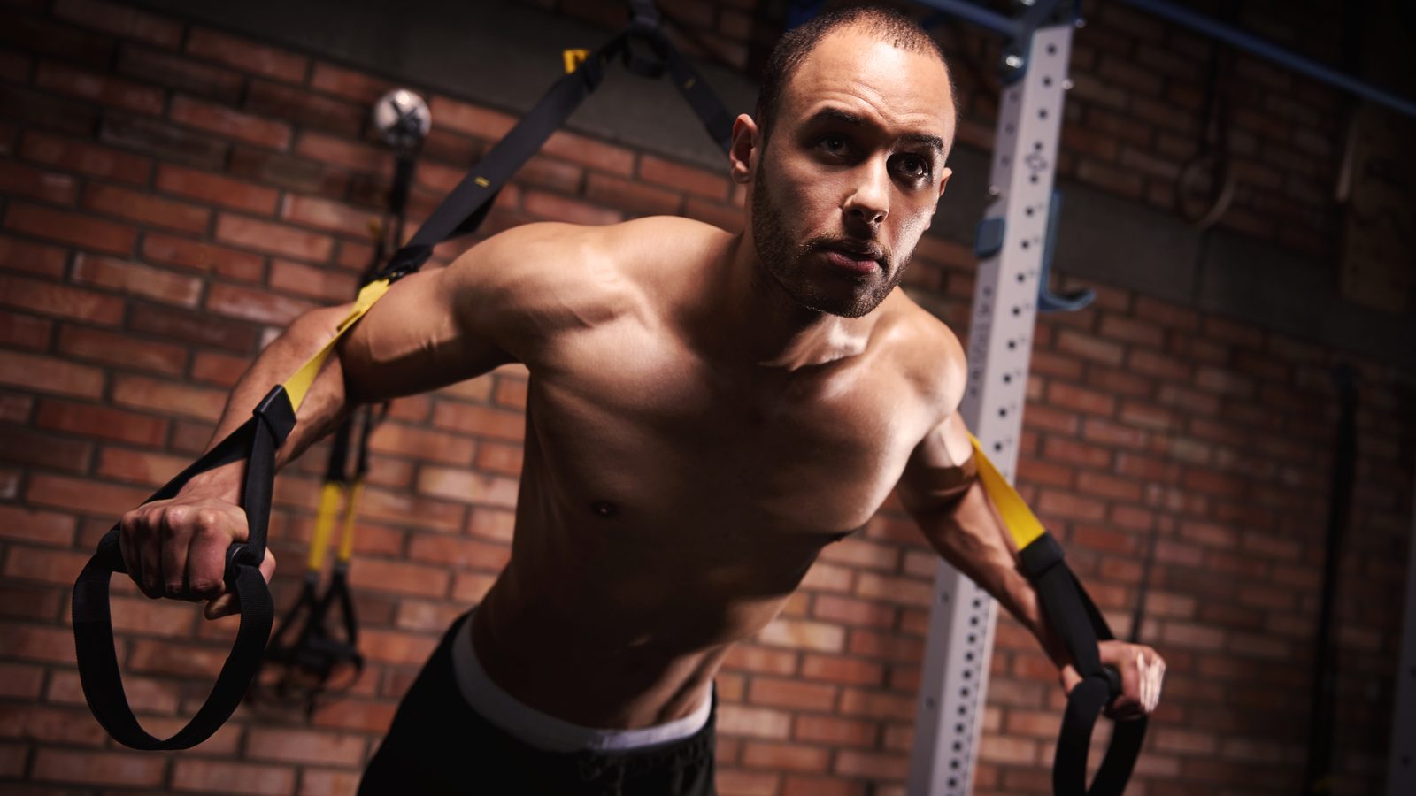 Homme travaillant la force des bras avec des bandes élastiques dans une salle d'entraînement