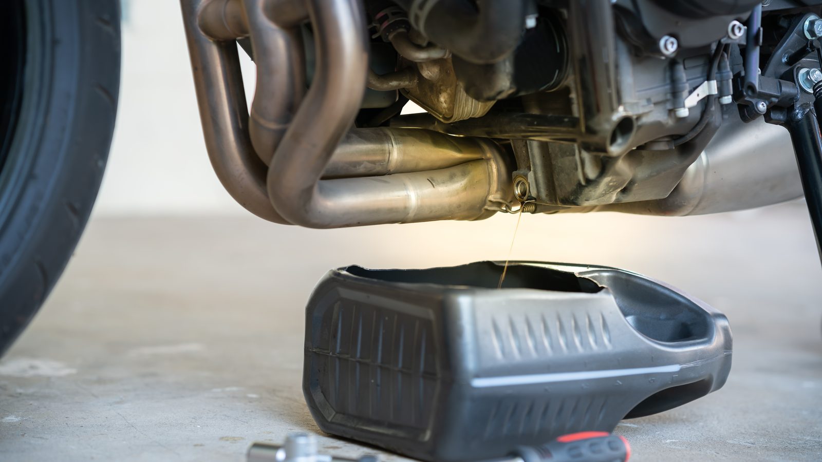 Huile moteur usagée s'écoulant par le bouchon de vidange d'un moteur de moto