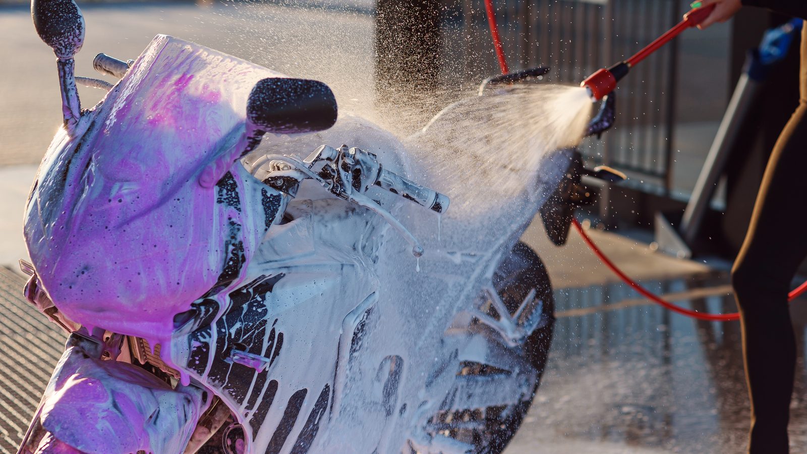 Lavage d'une moto au jet haute pression sur une aire de lavage en libre-service