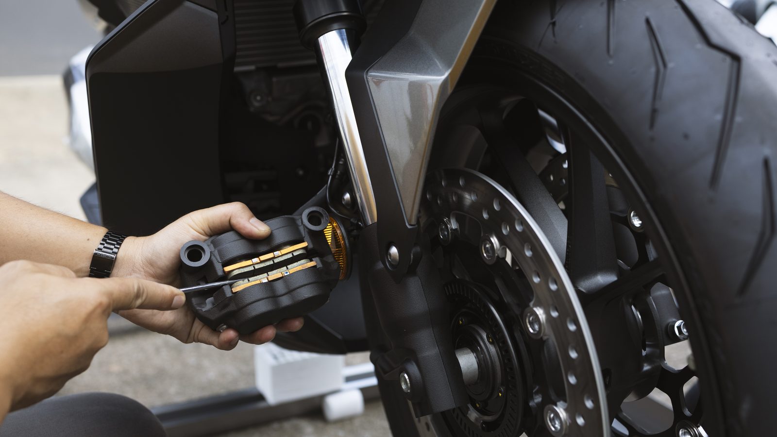 Main de mécanicien remplaçant les plaquettes de frein dans l'étrier d'une moto