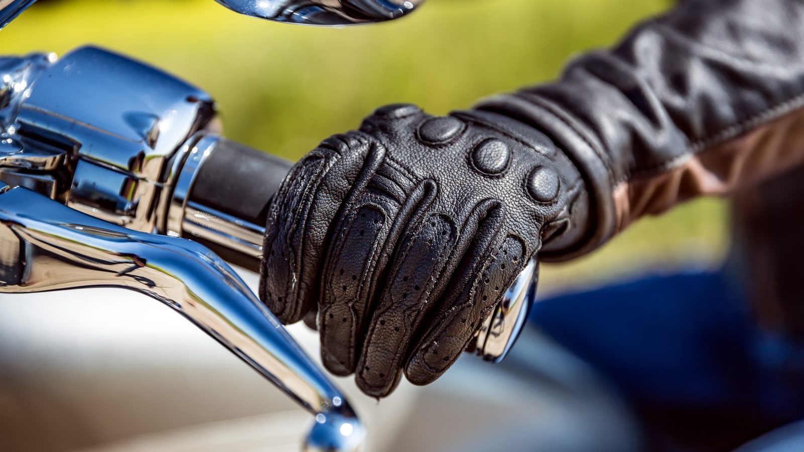 Main gantée refermée sur la poignée de gaz d'une moto, poignet légèrement abaissé