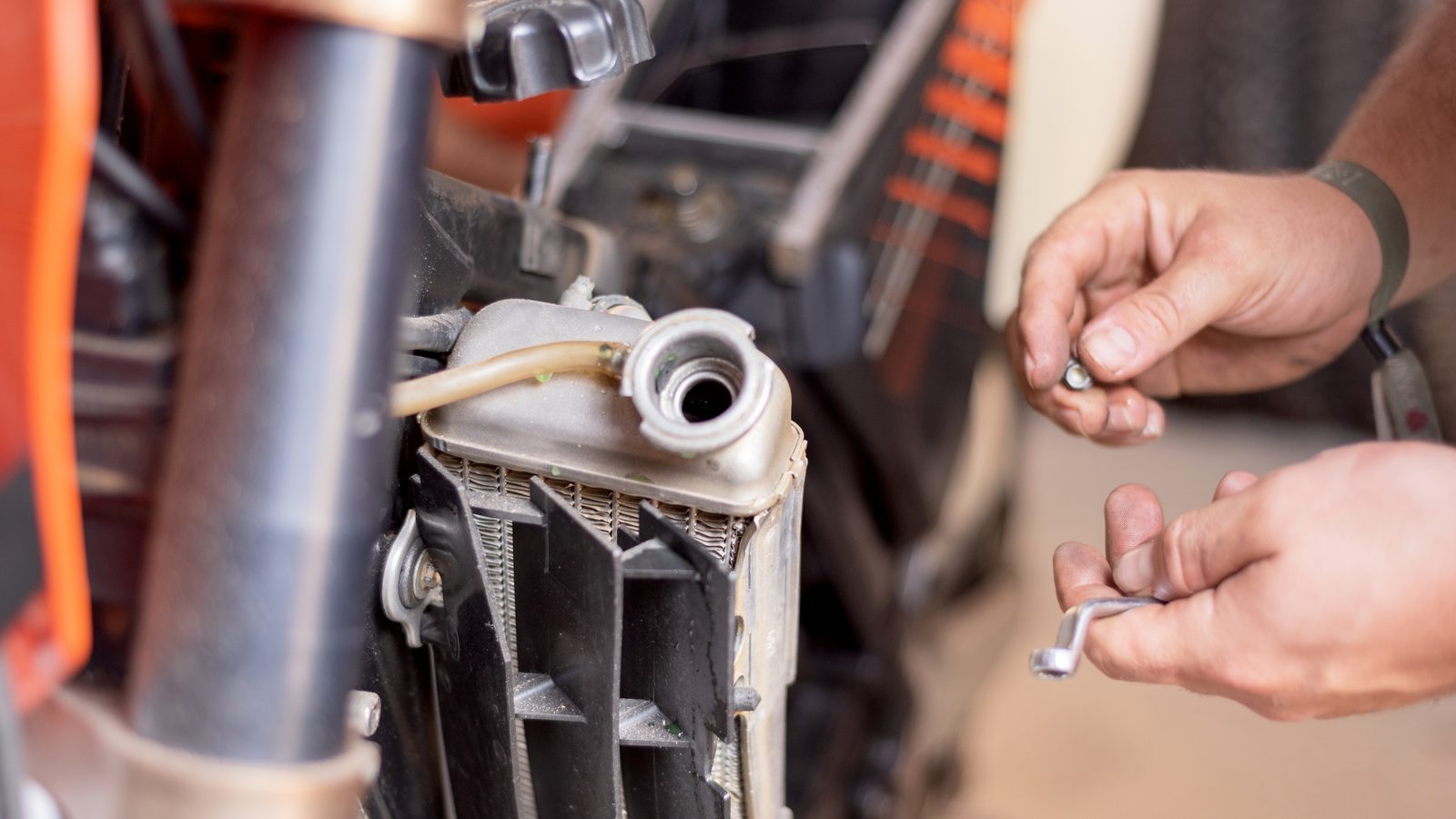 Mécanicien intervenant sur le radiateur de refroidissement d'une moto en atelier