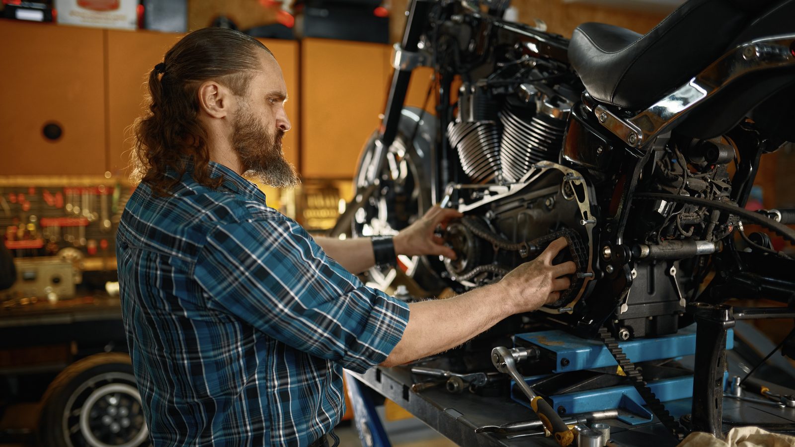 Mécanicien penché sur le moteur d'une moto dans un atelier, outils à portée de main
