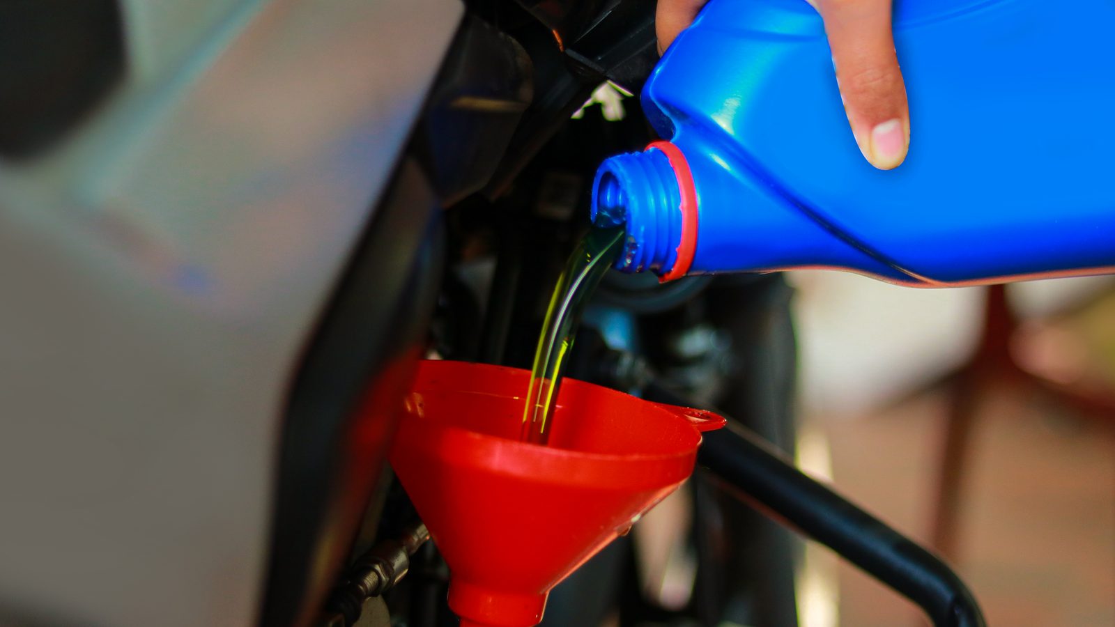 Motard versant de l'huile moteur neuve dans le moteur de sa moto