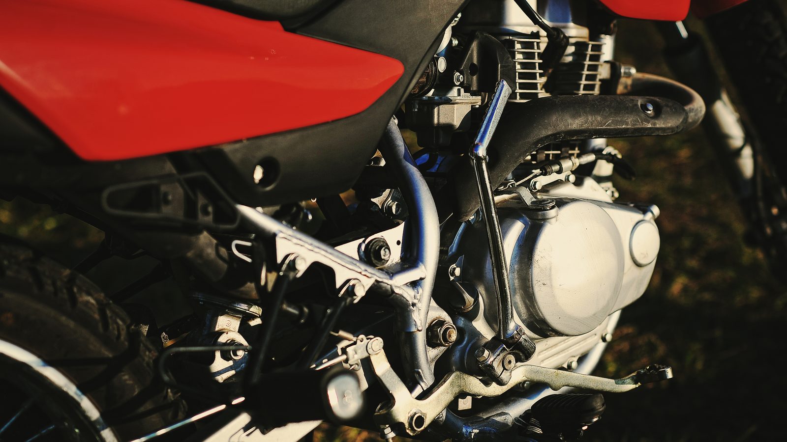 Moteur de moto tout-terrain vu de près, carters, culasse et tubes de cadre autour