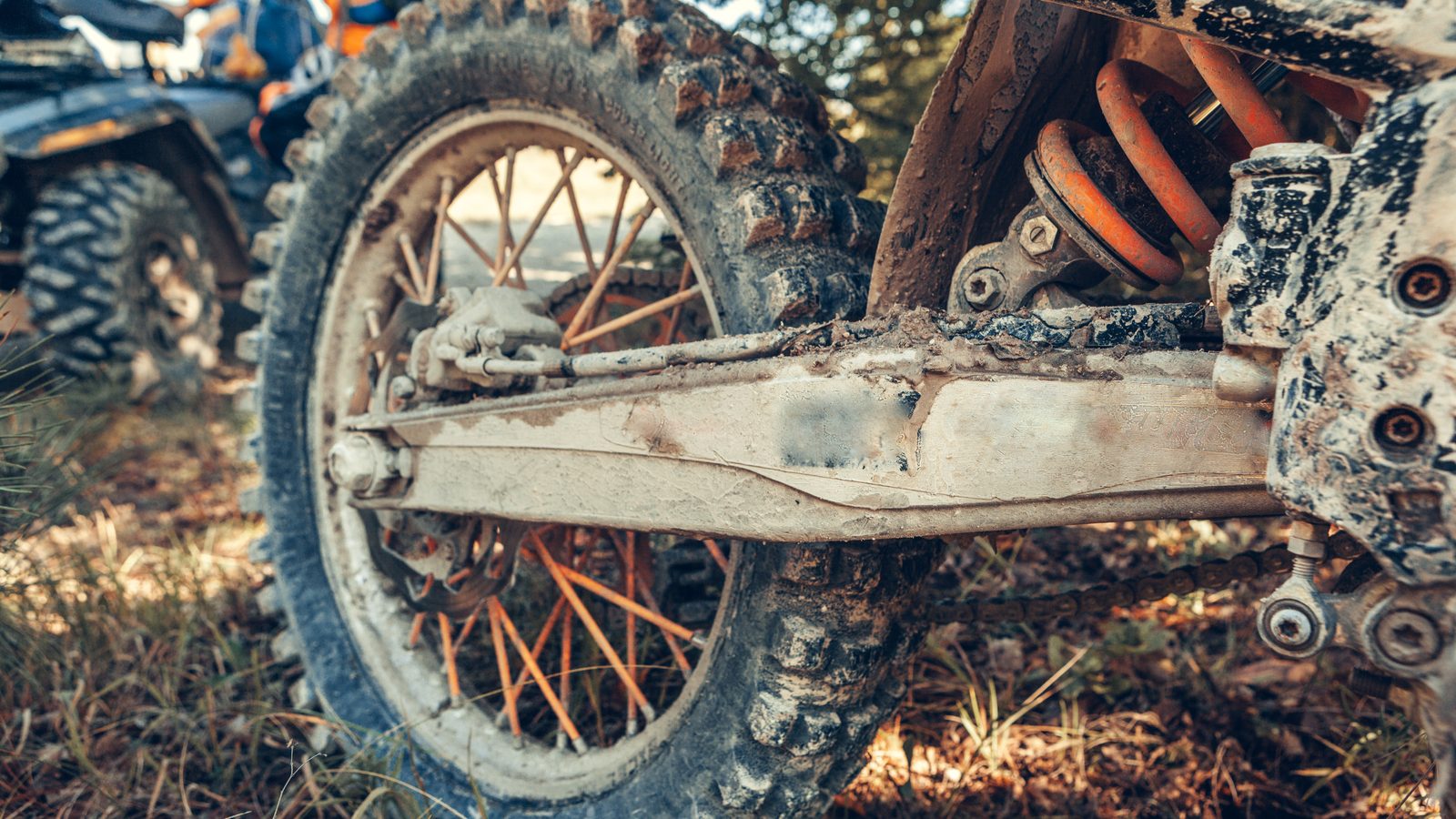 Moto de motocross posée au sol, cadre, réservoir et suspensions visibles de profil