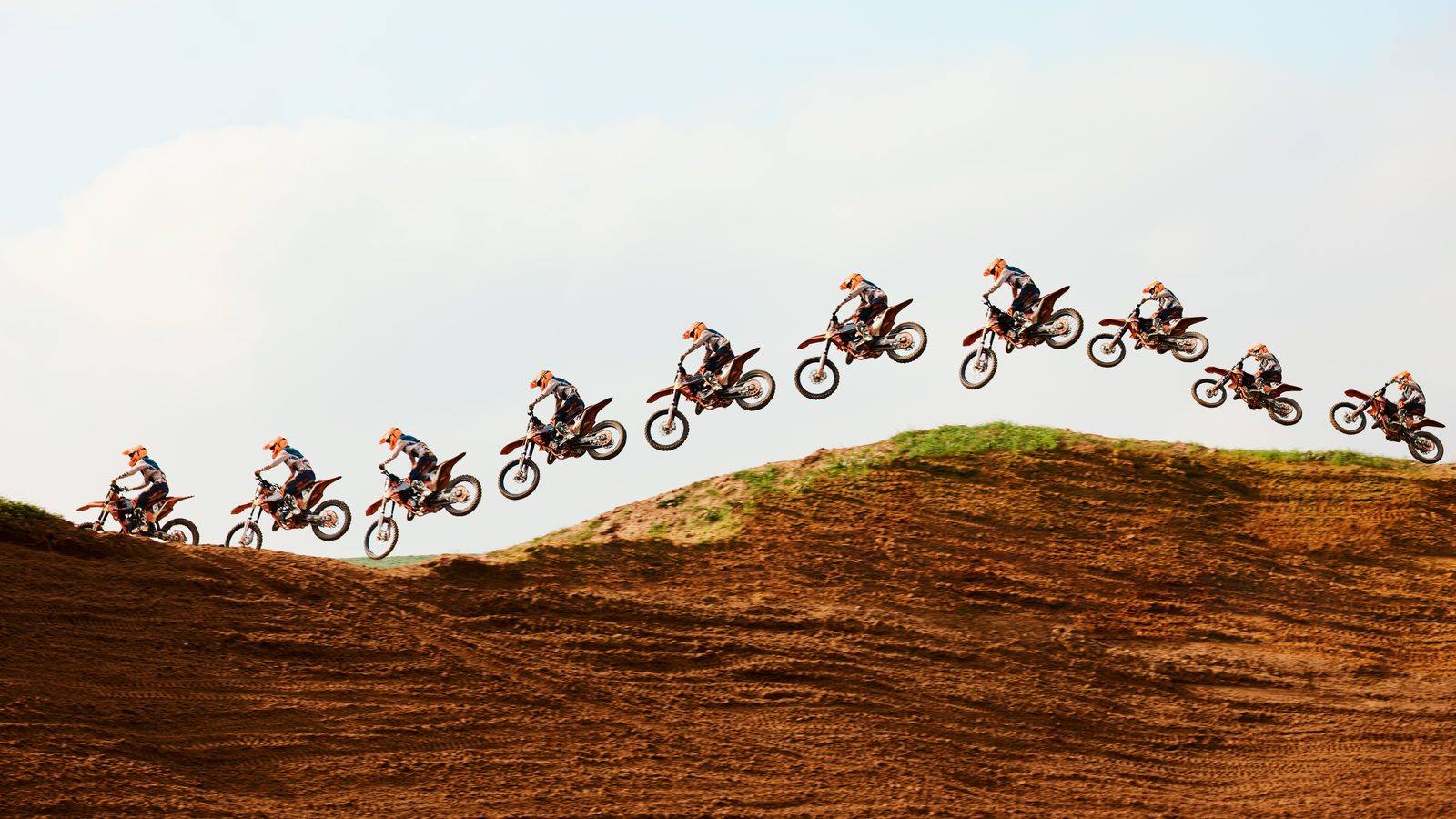 Moto tout-terrain au décollage sur la lèvre d'un tremplin, roue avant levée vers le ciel