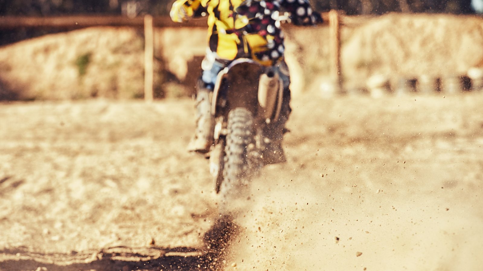 Moto tout-terrain soulevant un nuage de poussière sur une piste sableuse