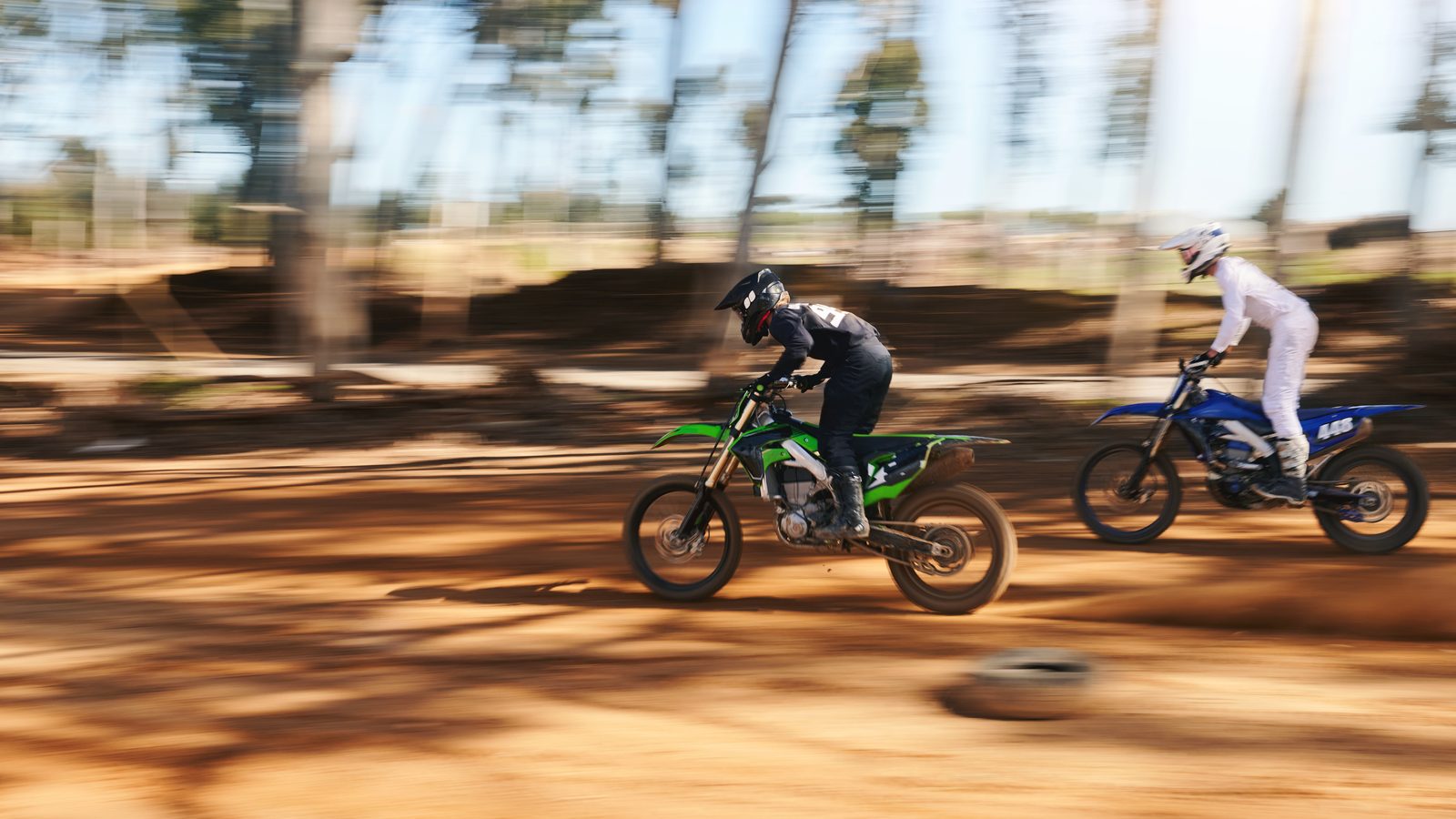Motos de motocross lancées à pleine accélération sur la ligne droite de départ, poussière soulevée
