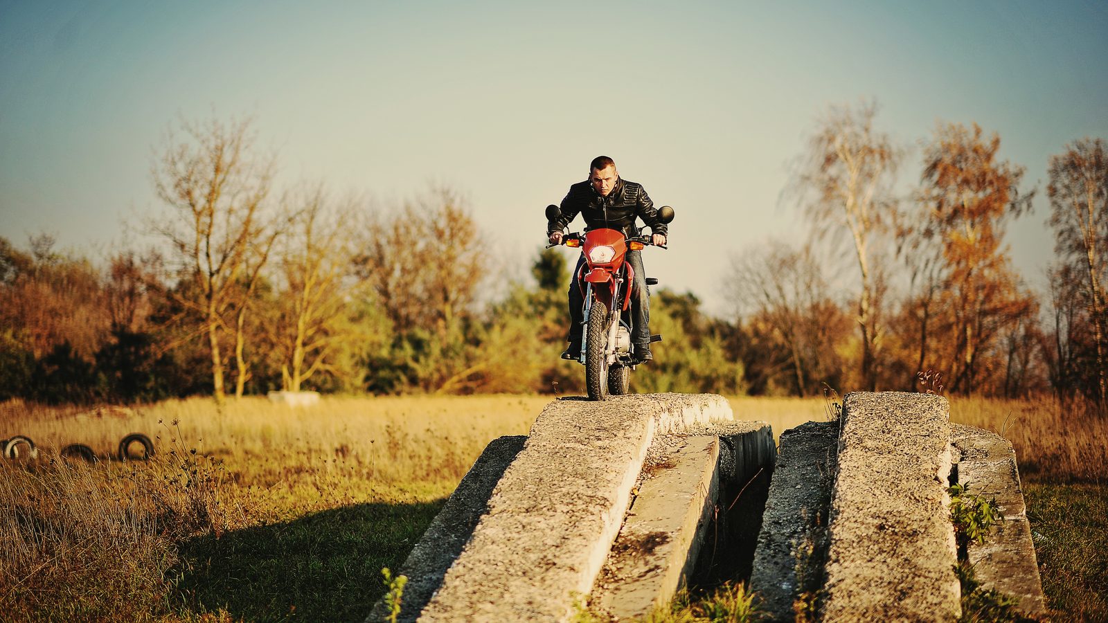 Pilote d'enduro assis en tenue sur sa moto, suspension comprimée sous son poids