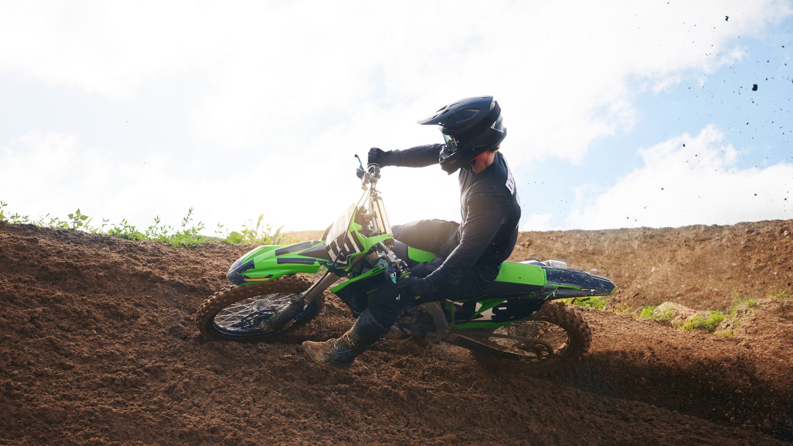 Pilote de moto tout-terrain en appui sur les freins à l'arrêt d'une portion de terre
