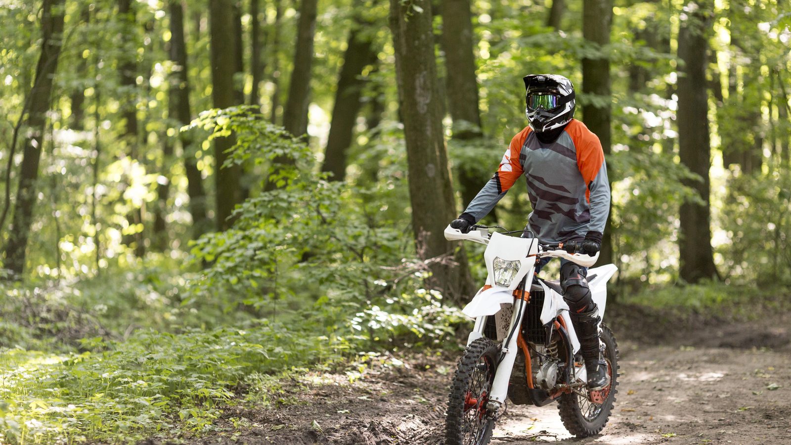 Pilote de moto tout-terrain en position de conduite sur un chemin, buste au-dessus du guidon