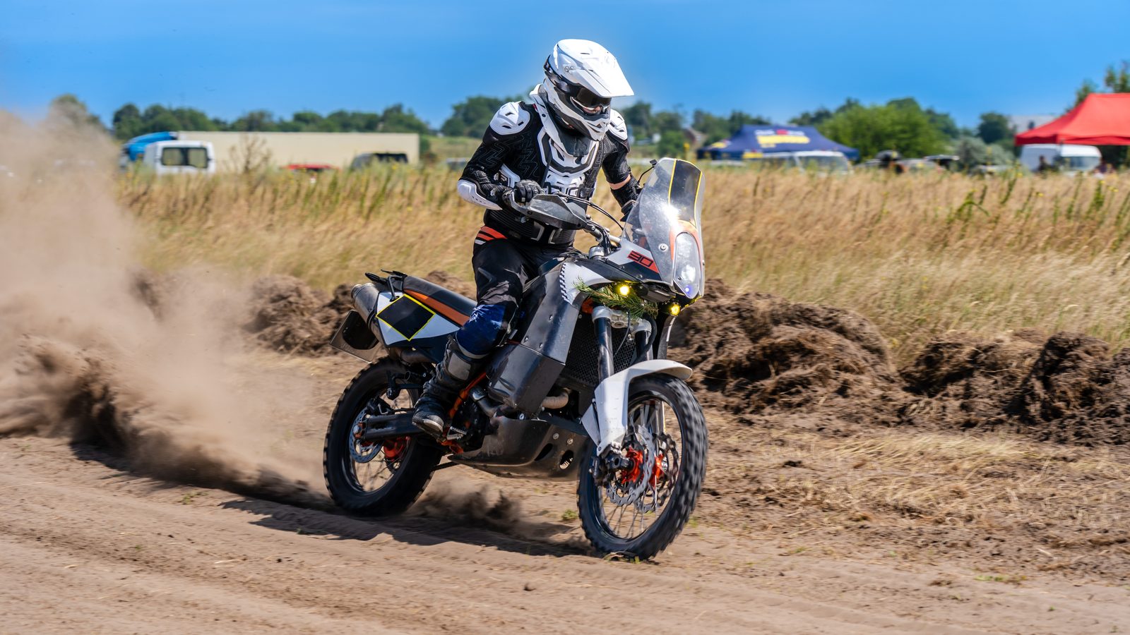 Pilote de motocross lancé sur une piste en terre, nuage de poussière derrière la roue arrière