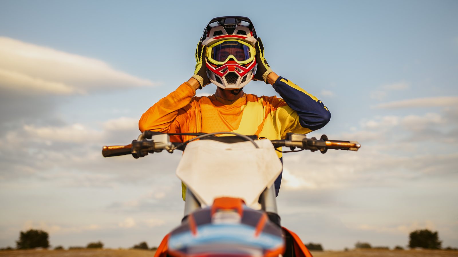 Pilote de motocross retirant son casque après une session, masque encore sur le front
