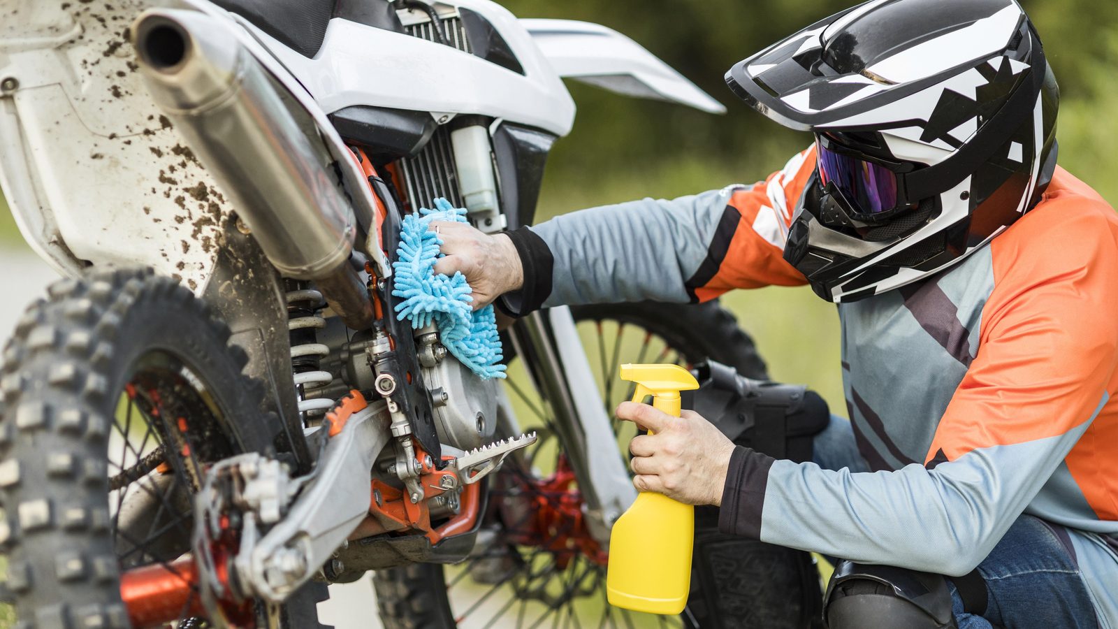 Pilote nettoyant sa moto tout-terrain en extérieur après une sortie