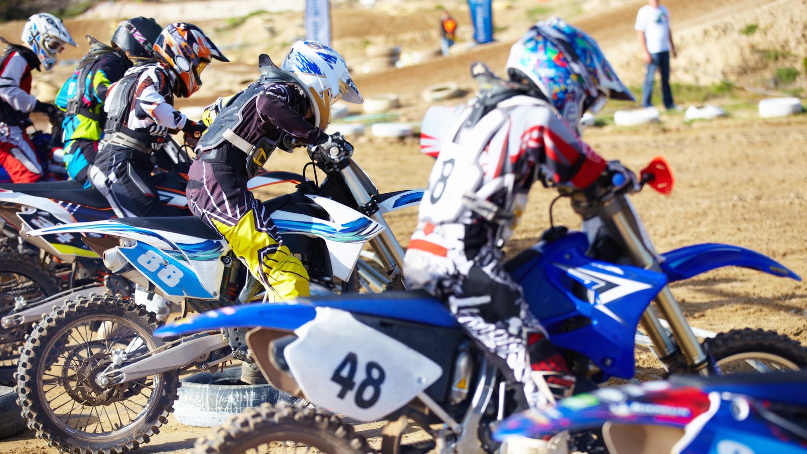 Pilotes de motocross alignés côte à côte, moteurs tournants, avant le lancement de la course