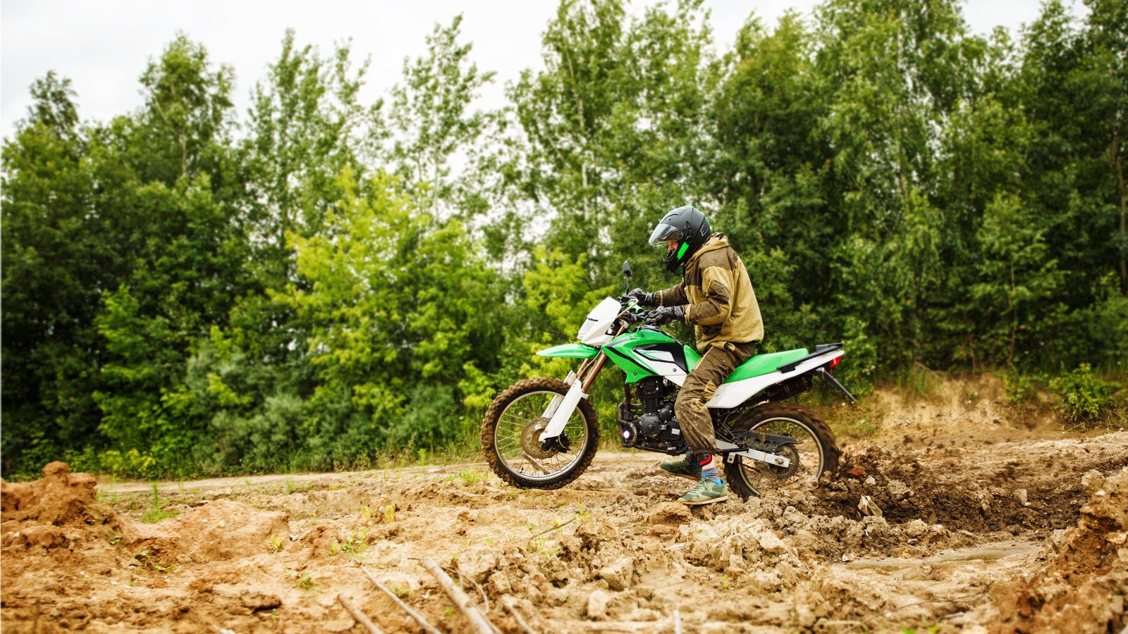 Roue arrière de moto tout-terrain patinant dans un sol gorgé d'eau, projections de terre humide
