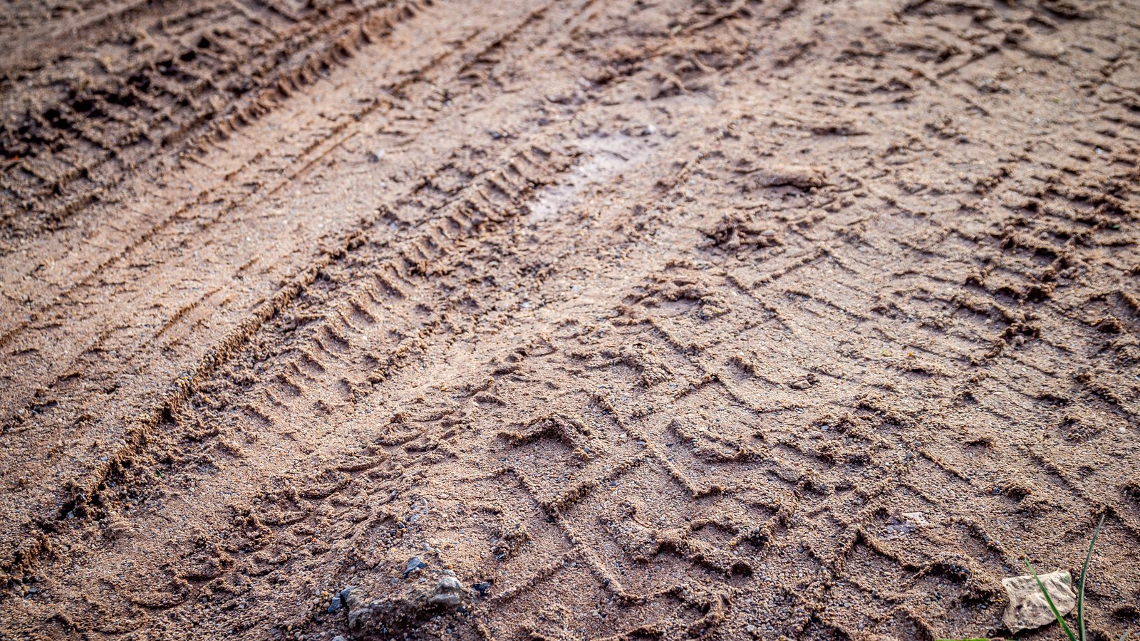 Trace de pneu profondément creusée dans un sol de terre humide, vue rapprochée du sillon