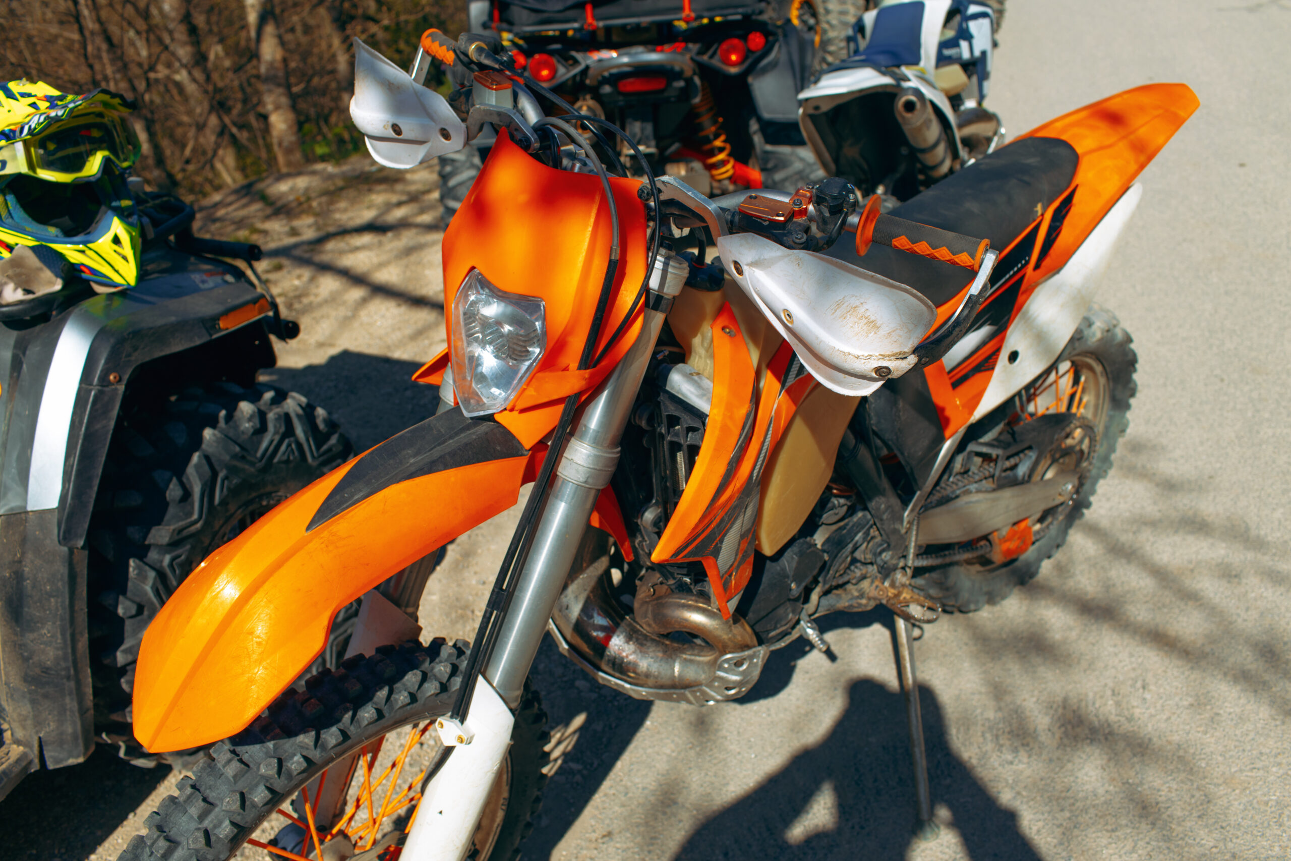 Gros plan sur une moto de motocross de compétition à l'arrêt, posée sur le sol, roues et suspensions bien visibles.