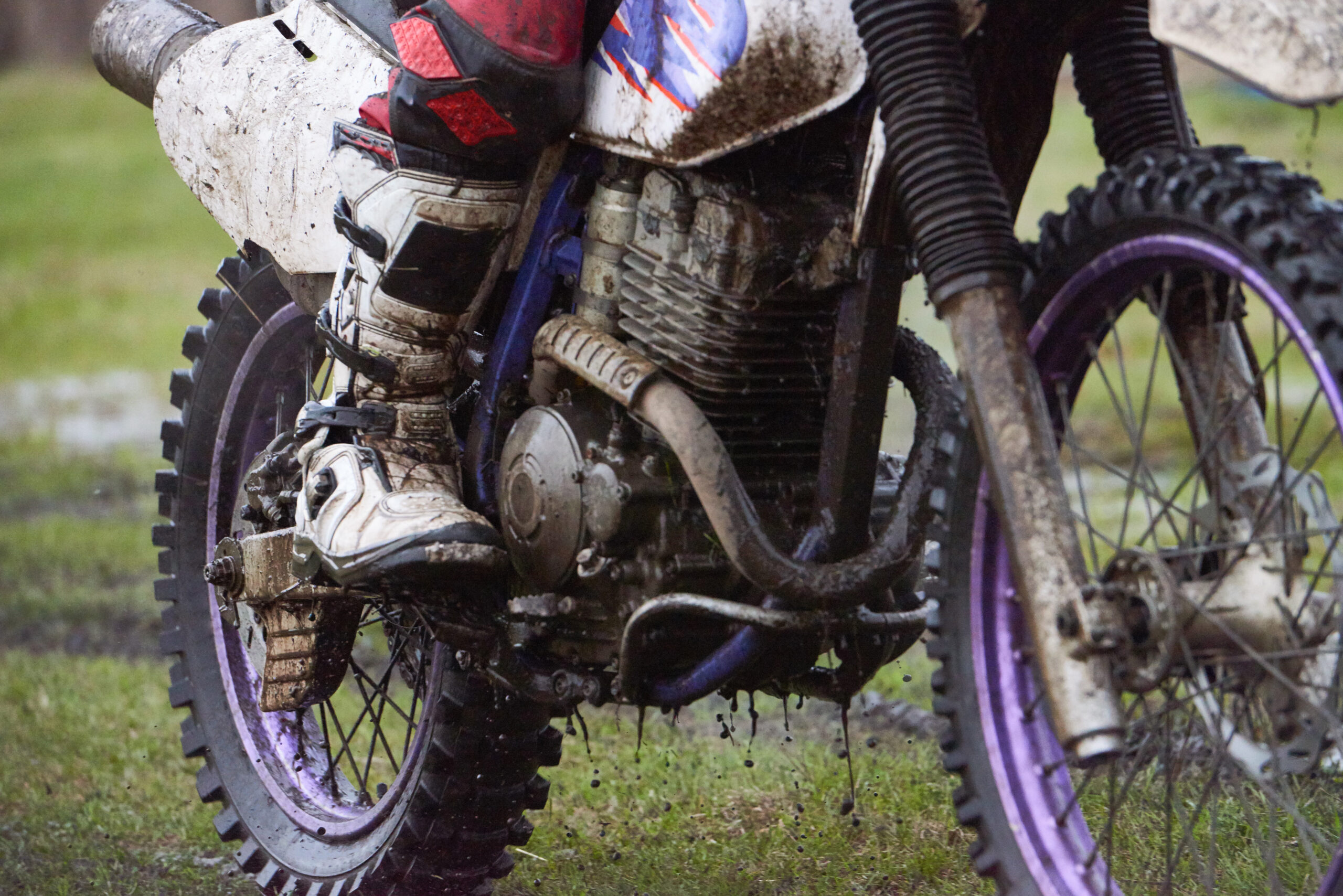Pilote de motocross assis sur sa moto pendant une course, plaque numéro et équipement de compétition bien visibles.