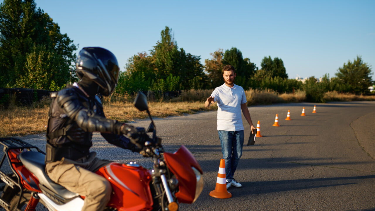 Moniteur de conduite qui explique les consignes à un élève casqué avant un exercice sur le terrain d'entraînement.