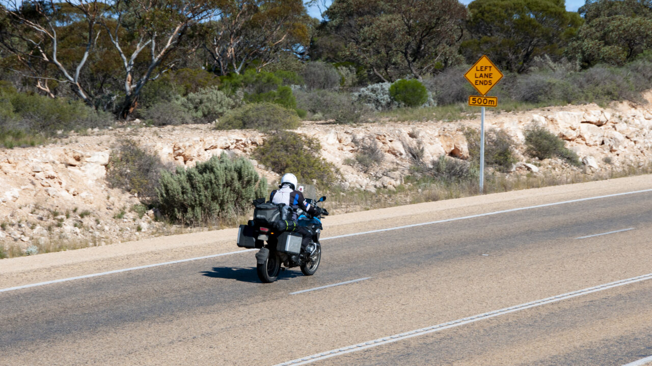 Motard roulant sur une route goudronnée avec une moto de type enduro homologuée pour un usage sur voie publique.