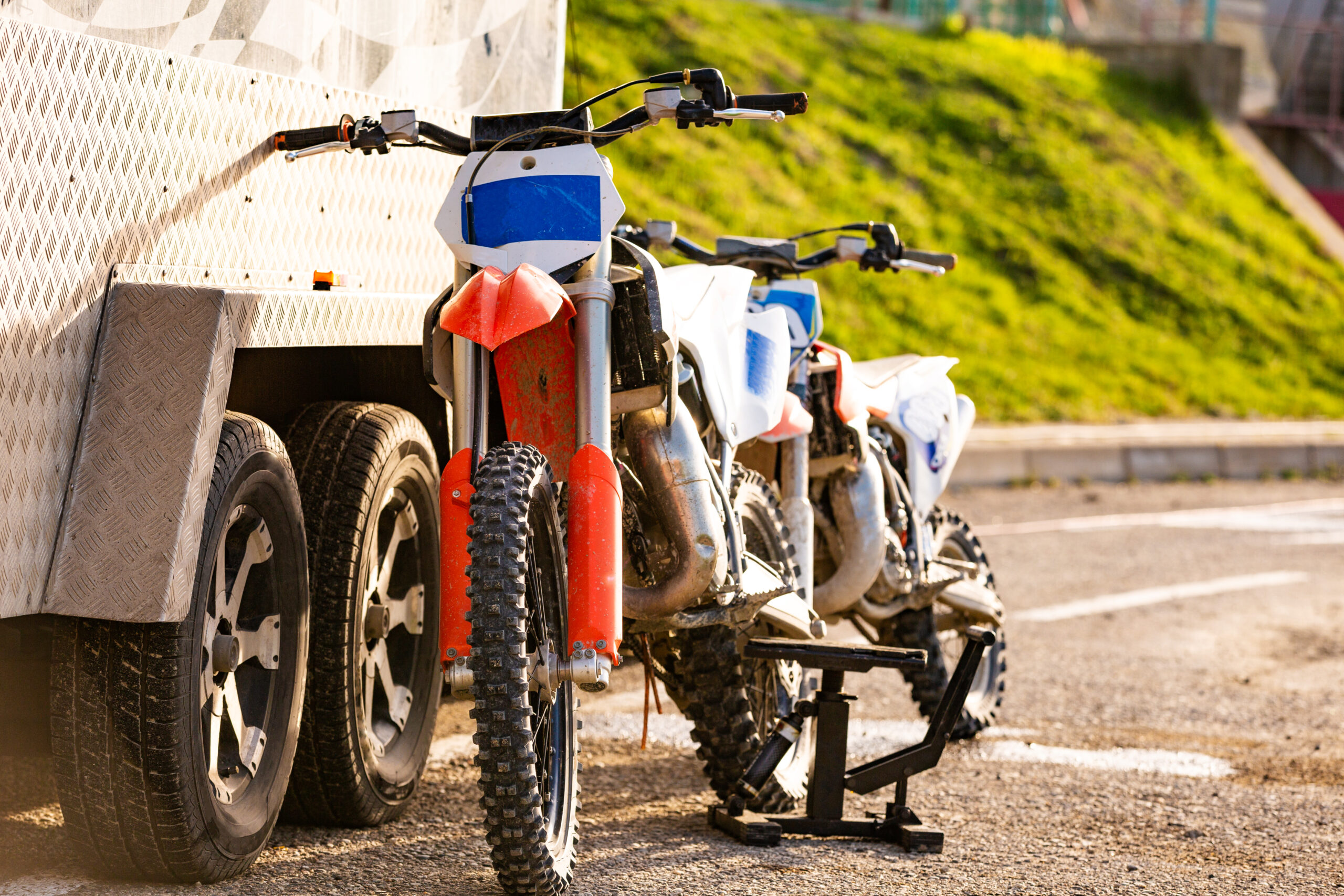 Plusieurs motos tout-terrain garées côte à côte sur une aire de stationnement, prêtes à repartir sur le circuit.