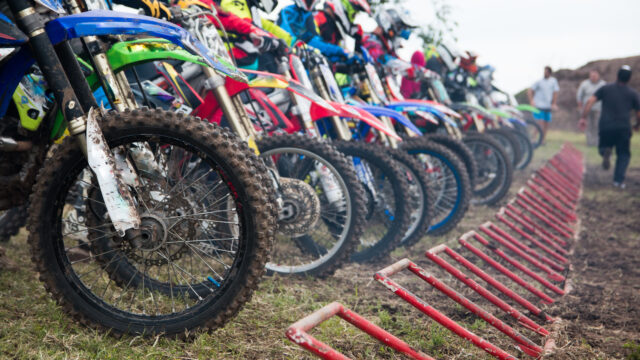 Pilotes de motocross alignés à la grille de départ, moteurs allumés, prêts à disputer leur première course.