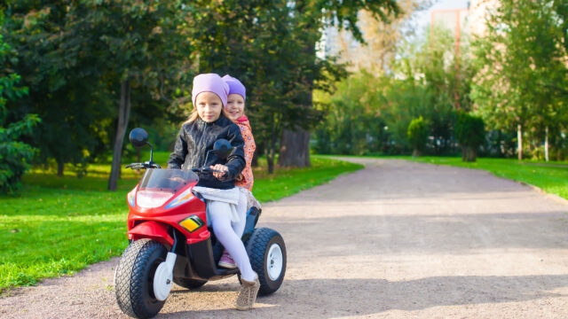 Jeune enfant qui roule sur une petite moto cross adaptée à son âge, dans un cadre verdoyant en plein air.