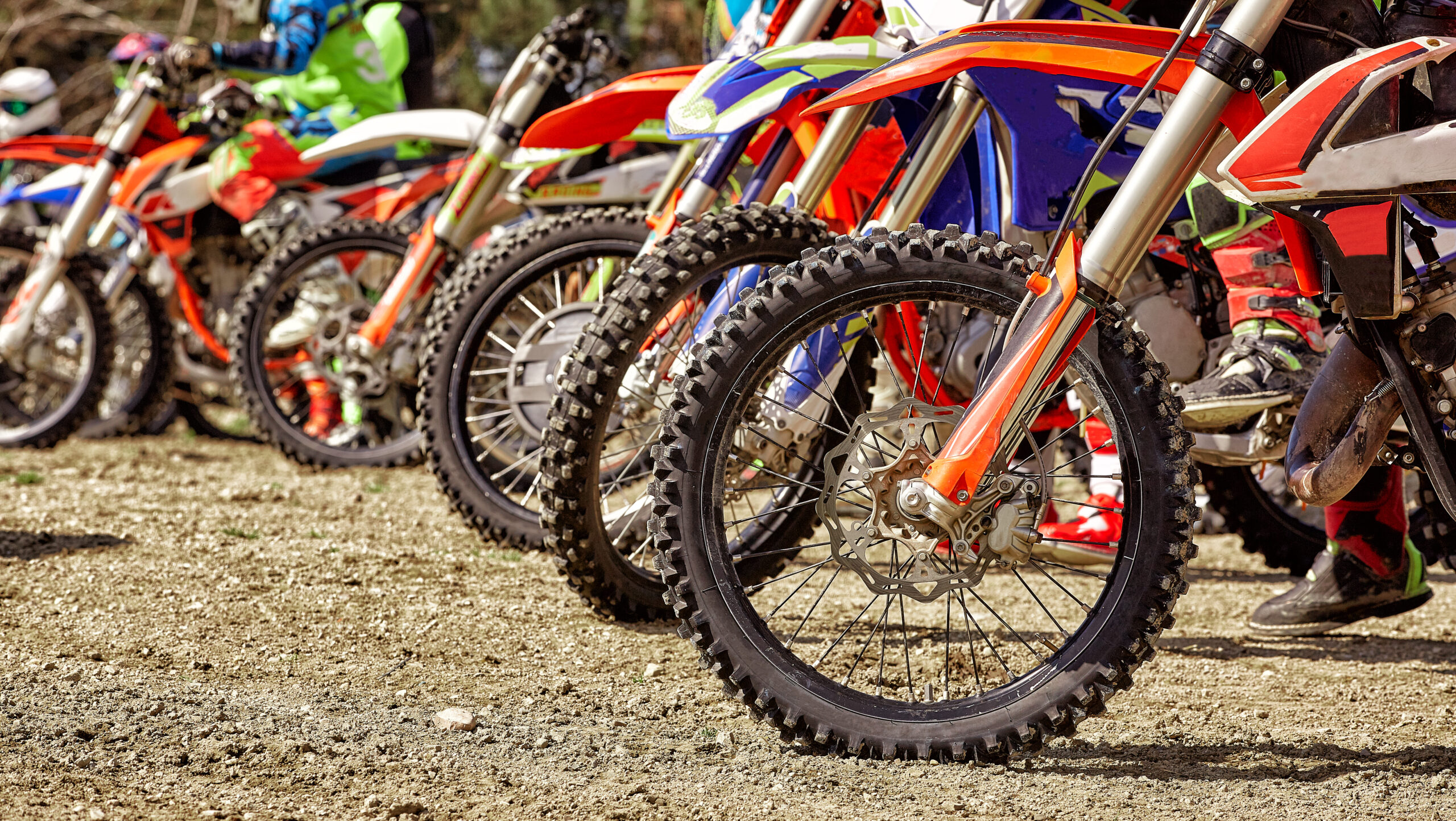 Groupe de pilotes de motocross installés sur leurs motos au départ, prêts à s'engager sur la piste.