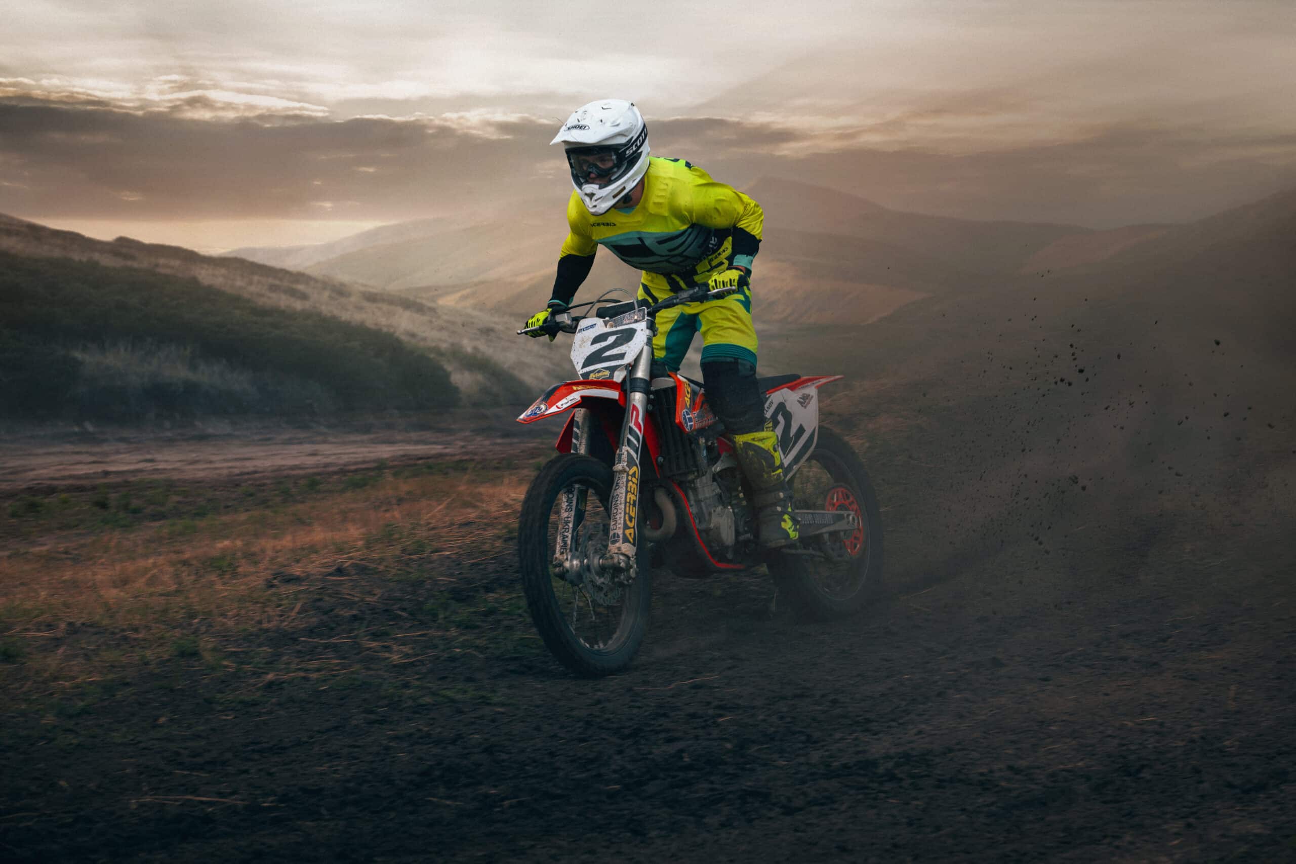 Pilote de motocross lancé sur une piste sèche, nuage de poussière soulevé par la roue arrière